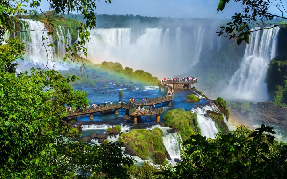 People gather at a viewpoint over Iguazu Falls in Brazil and watch the waterfall.