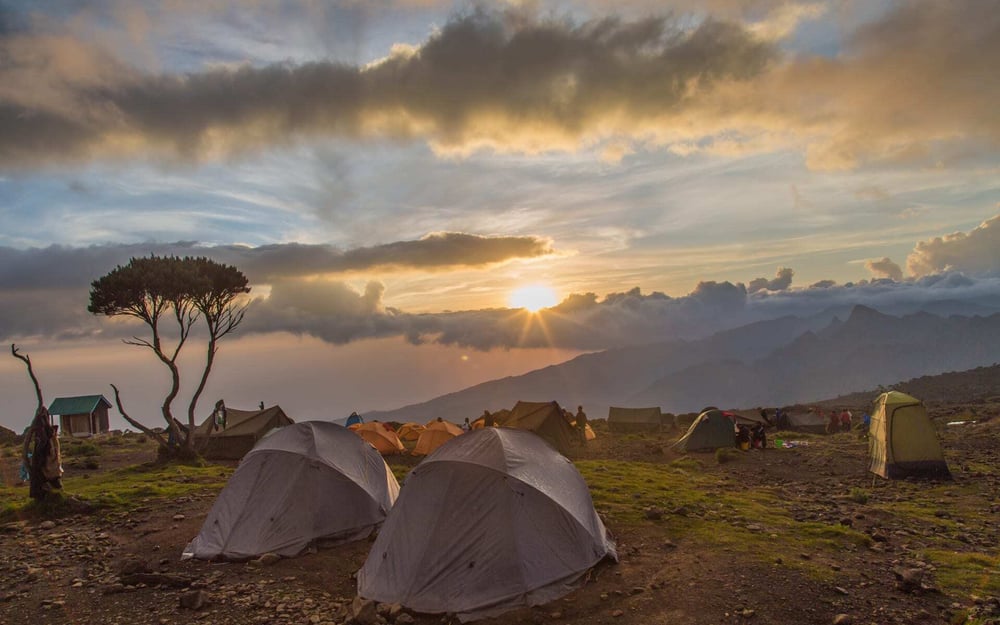 A tented Camp on Mount Kiliminjaro faces a sunrise after rainfall.