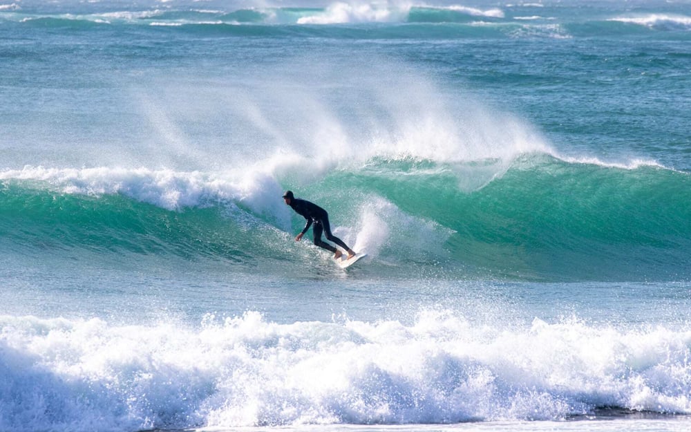 A man surfs high waves in Katsuura wearing a wet suit.