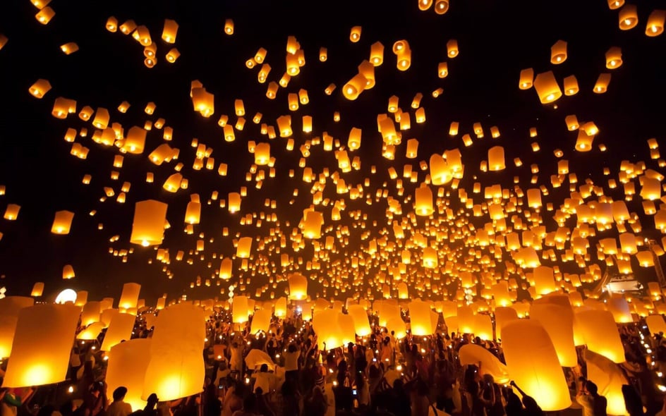 Colorful floating lanterns lighting up the night sky during a festival in Chiang Mai, Thailand.
