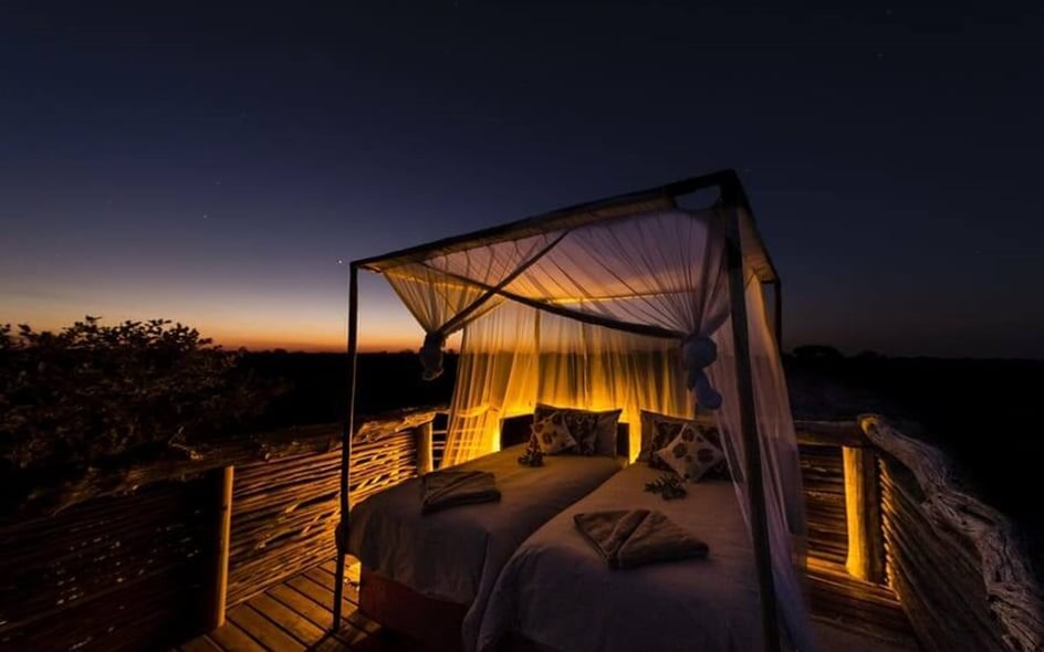 A bed is situated outside ahead of a clear night sky.