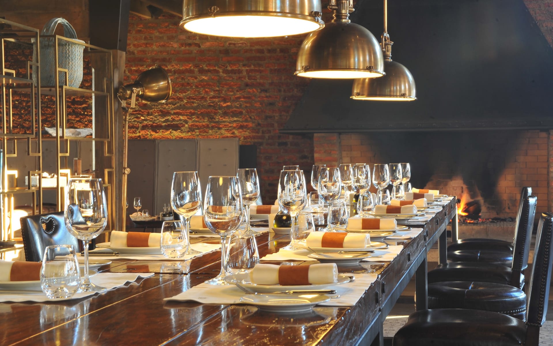 A dining table is readied with wine glasses, plates and napkins. 