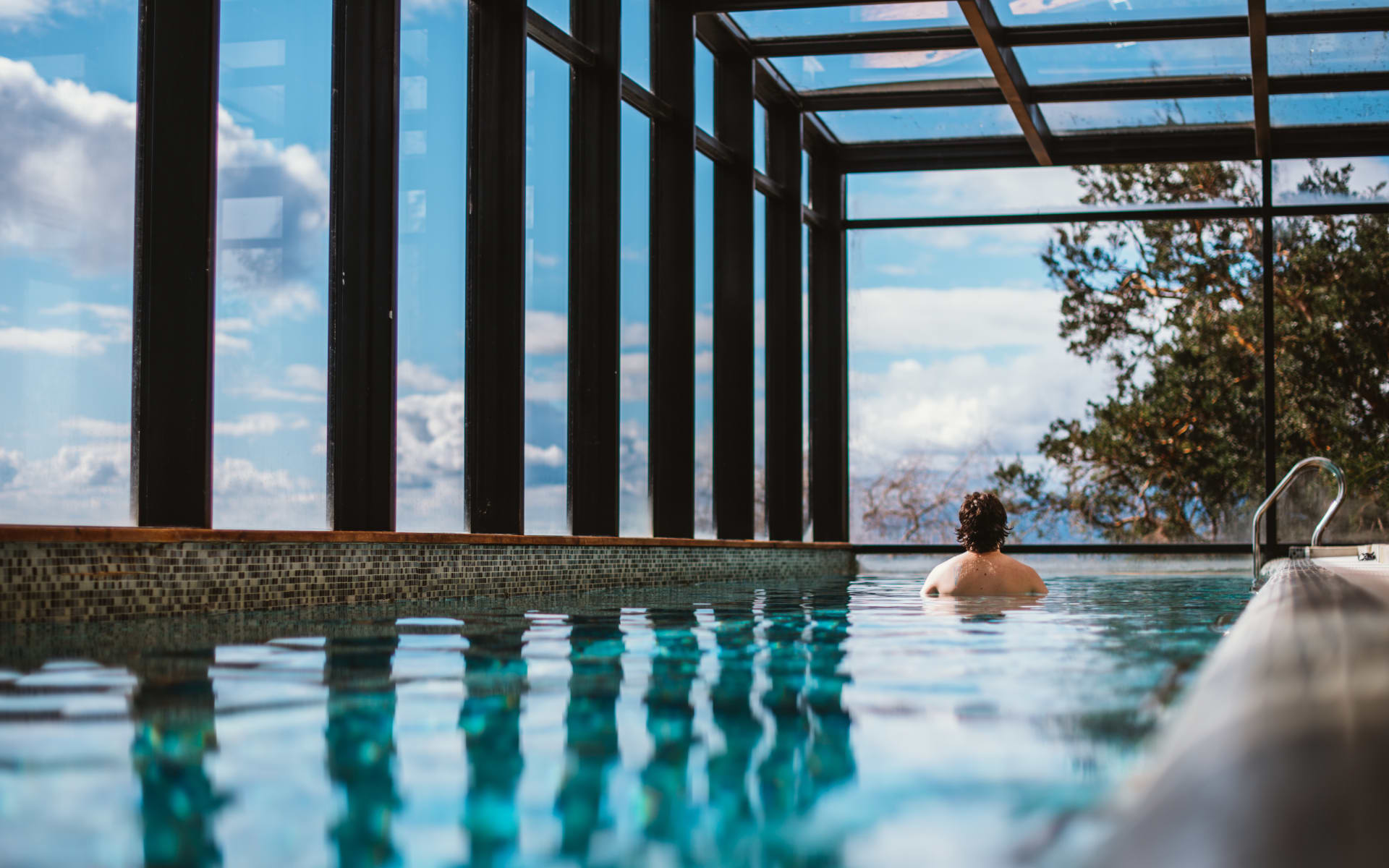 A man is swimming in a rectangular-shaped swimming pool. 