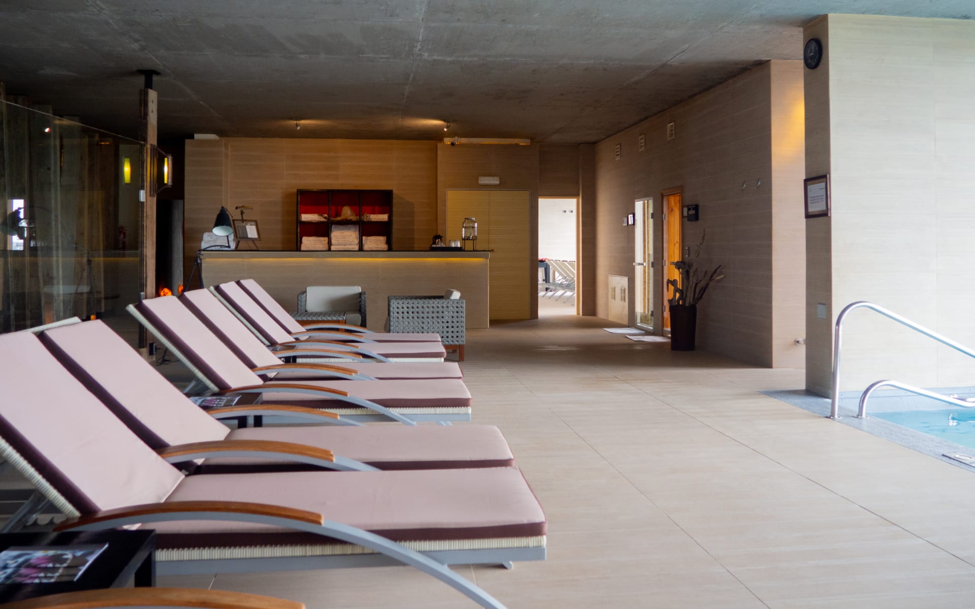Sun loungers overlook an indoor swimming pool.