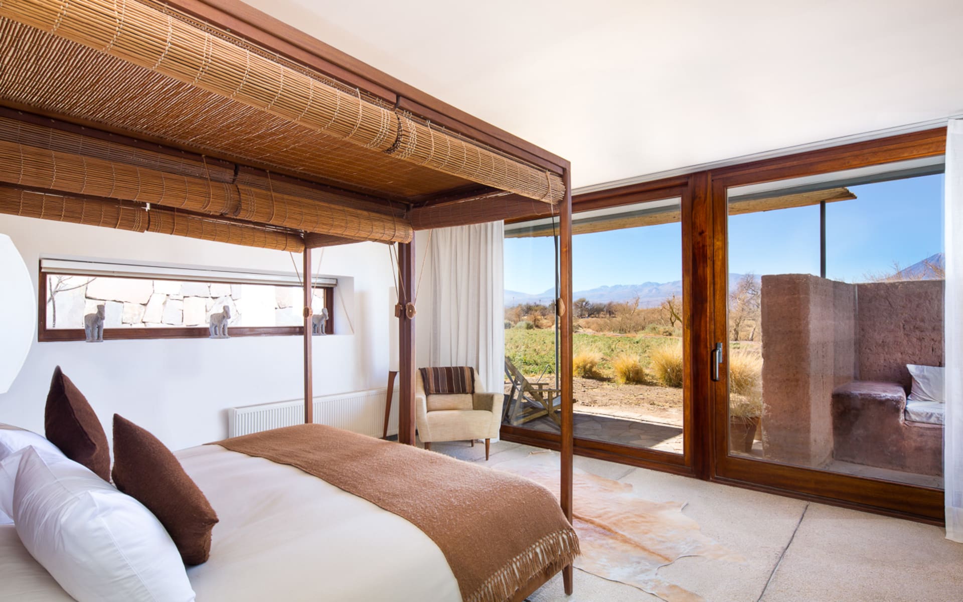 A canopy bed looks out of floor-to-ceiling windows that open to the garden. 
