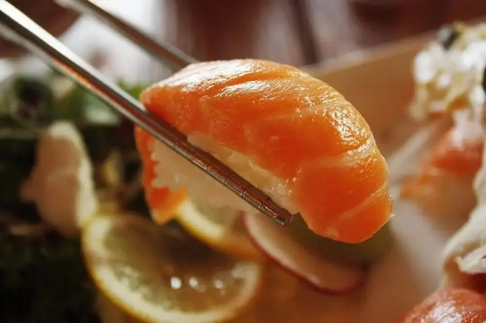salmon-sushi-held-between-chopsticks-1-1