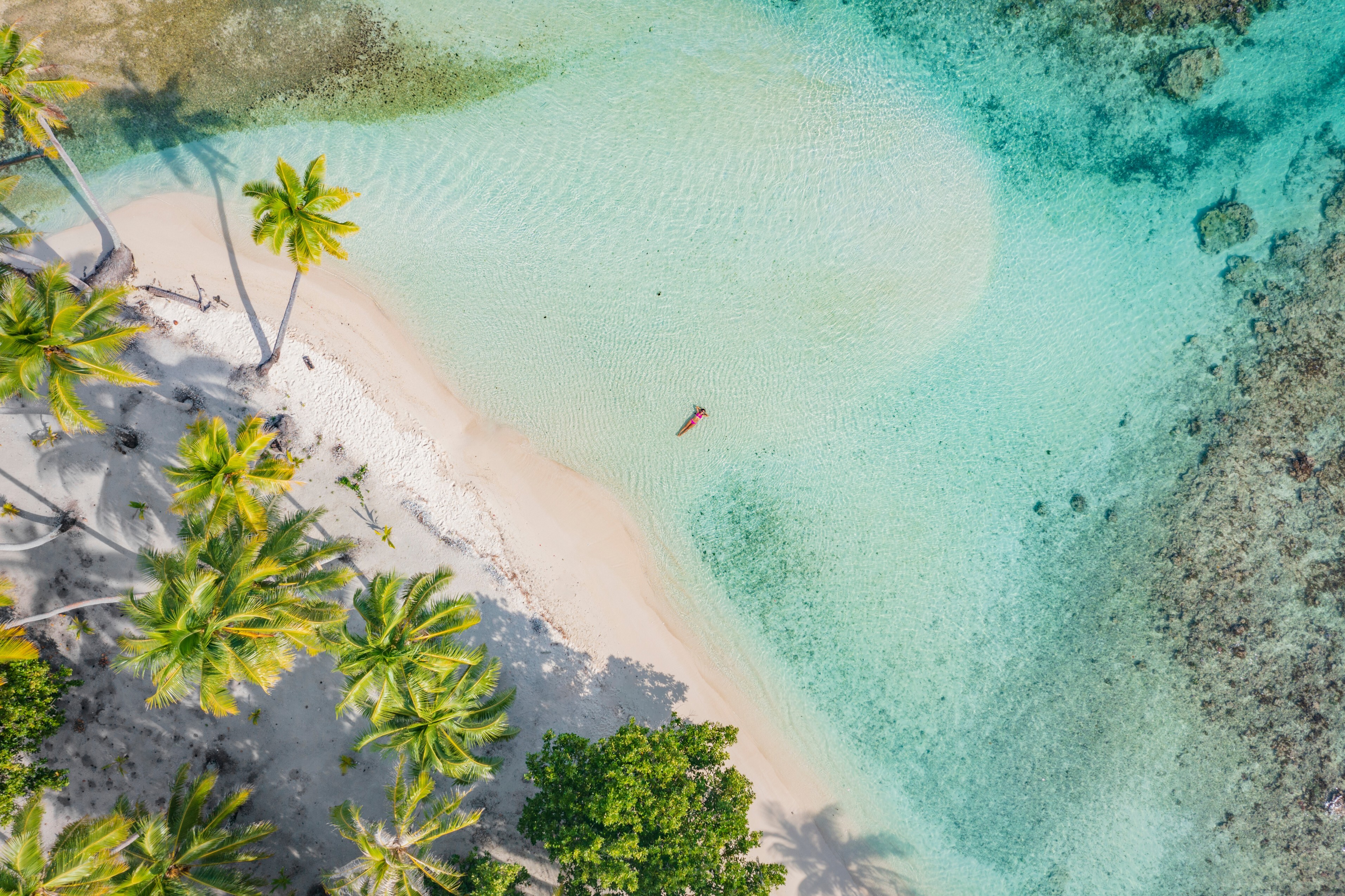 A tourist relaxes in the turquoise shores of the Maldives.